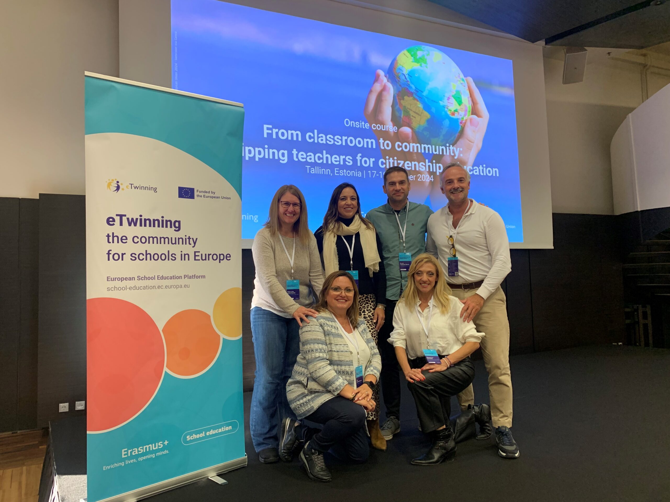 Imagen con los asistentes y el cartel del evento